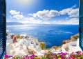 View through an open window with shutters of the whitewashed village of Oia rising above the blue Aegean Sea and the caldera on the island of Santorini, Greece.