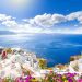 View through an open window with shutters of the whitewashed village of Oia rising above the blue Aegean Sea and the caldera on the island of Santorini, Greece.