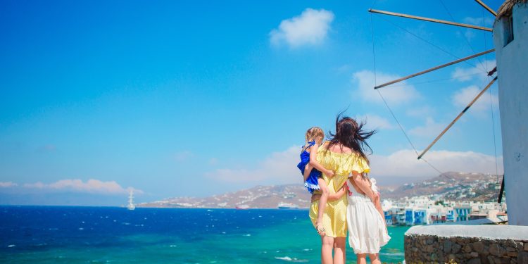 Happy family in front of windmills at popular tourist area on Mykonos island, Greece