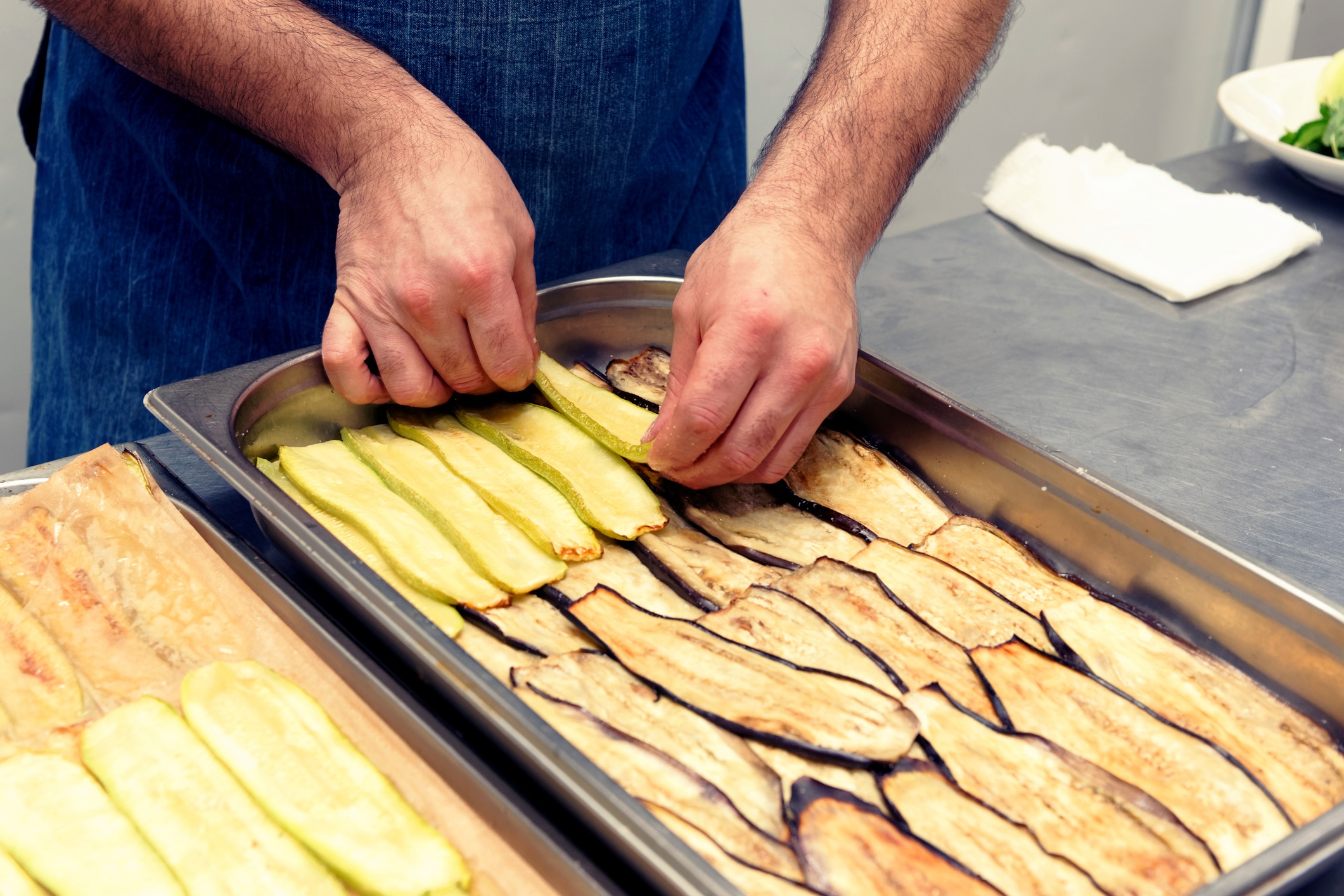 Chef is making layers of vegetables to cook Greek moussaka, professional kitchen, toned