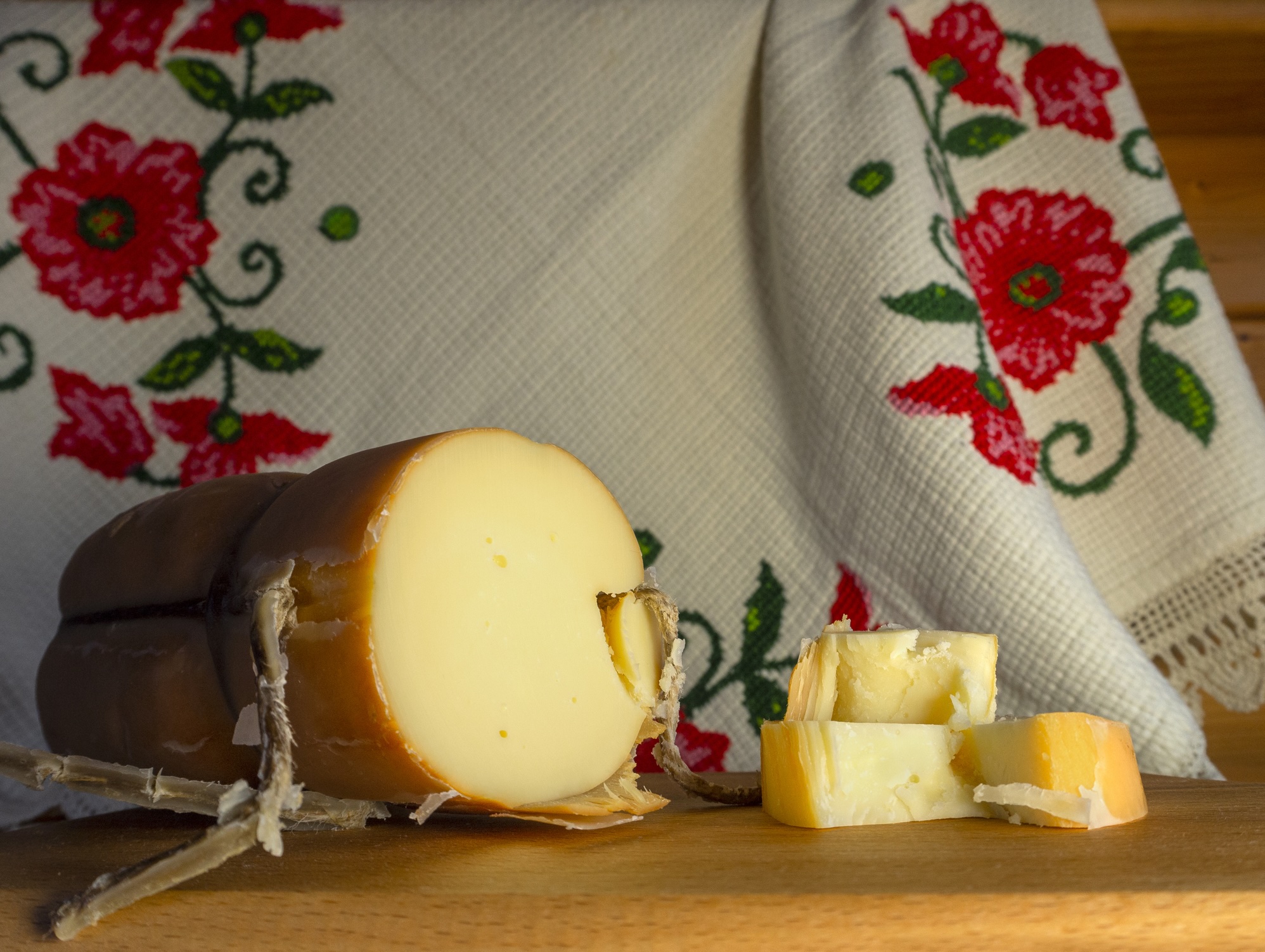 Traditional Greek smoked cheese Metsovone on a wooden board with grapes from the village Metsovo in Greece