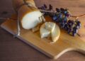 Traditional Greek smoked cheese Metsovone on a wooden board with grapes from the village Metsovo in Greece