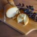 Traditional Greek smoked cheese Metsovone on a wooden board with grapes from the village Metsovo in Greece